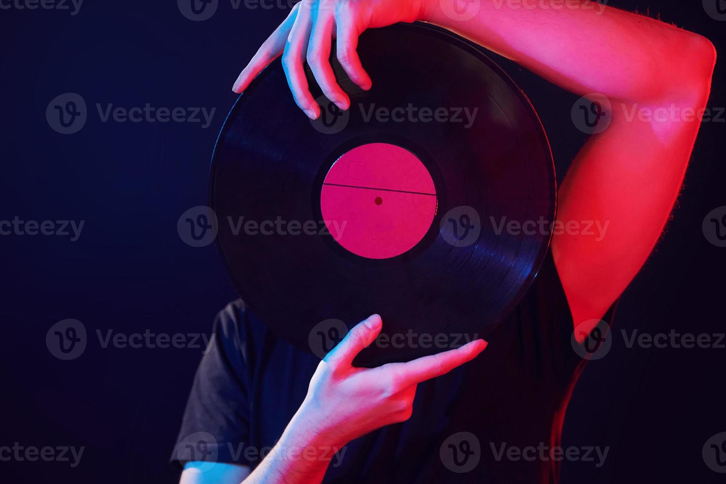 in possesso di un disco in vinile. uomo in piedi in studio con luce al neon foto