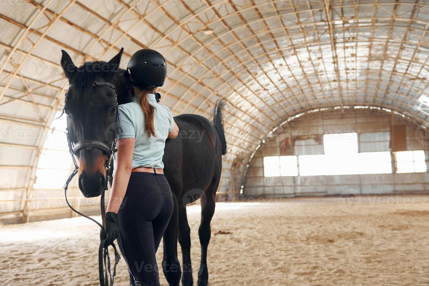 concezione della cura. una giovane donna in abiti da fantino si sta preparando per un giro con un cavallo in una stalla foto