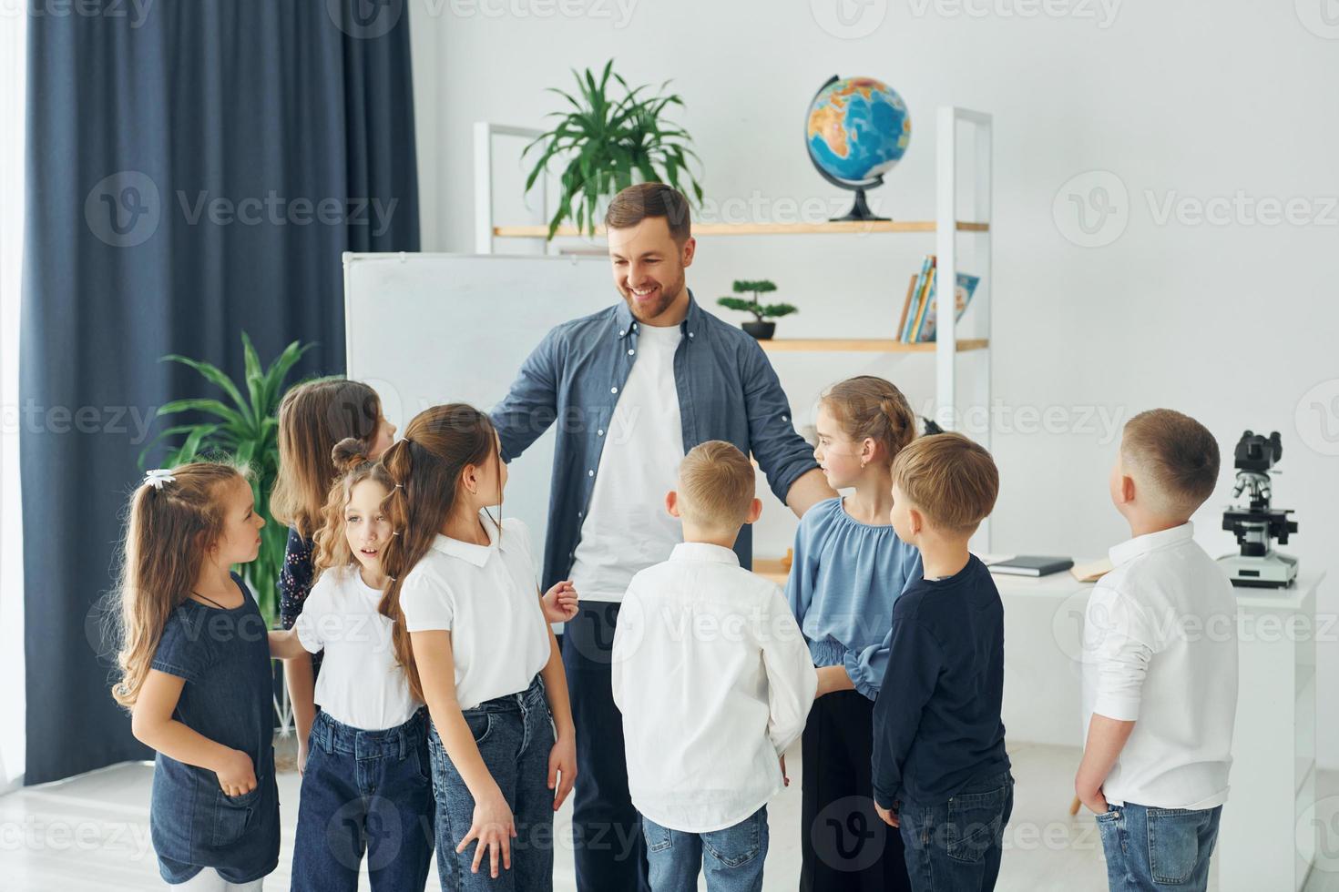 in piedi e dando il cinque. gruppo di bambini studenti in classe a scuola con l'insegnante foto