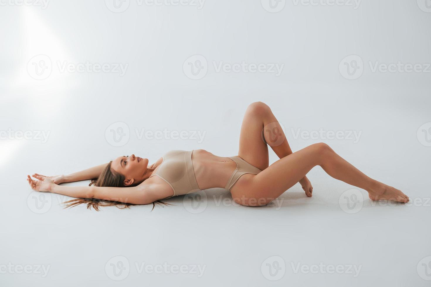 sul pavimento. donna in biancheria intima con tipo di corpo snello sta posando in studio foto