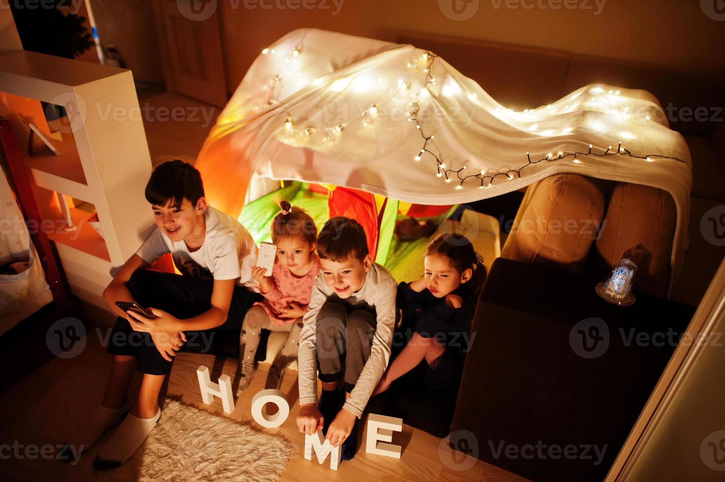 bambini in tenda che guardano la tv di notte a casa. umore hygge. foto