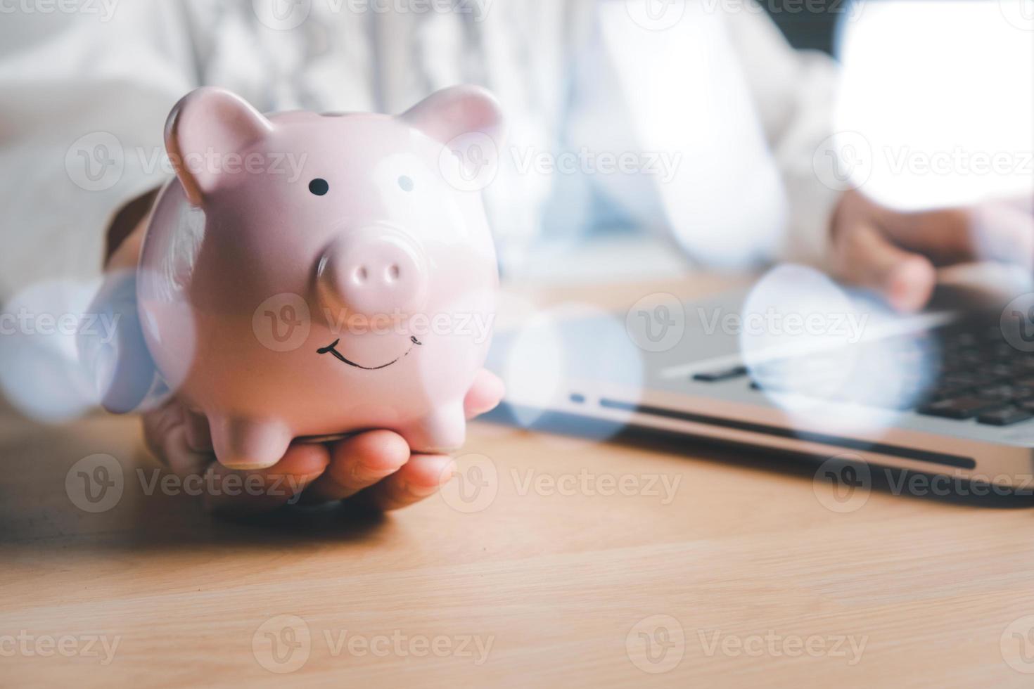 mano della donna che tiene salvadanaio sul tavolo di legno, concetto di investimento finanziario, affari, finanza, investimento, pianificazione finanziaria. foto