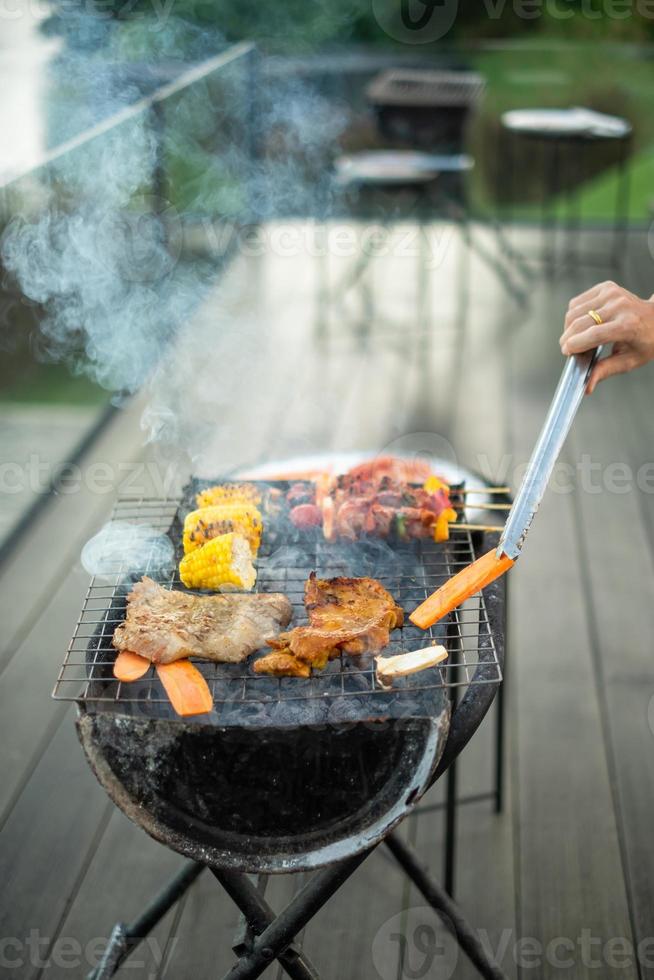 deliziosa carne alla griglia con fumo, barbecue con verdure all'aperto. concetto di barbecue, festa, stile di vita e picnic foto