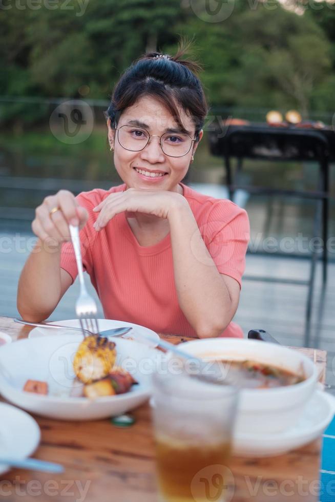 donna felice che mangia la cena con deliziosa carne alla griglia e barbecue all'aperto. concetto di barbecue, festa, stile di vita e picnic foto