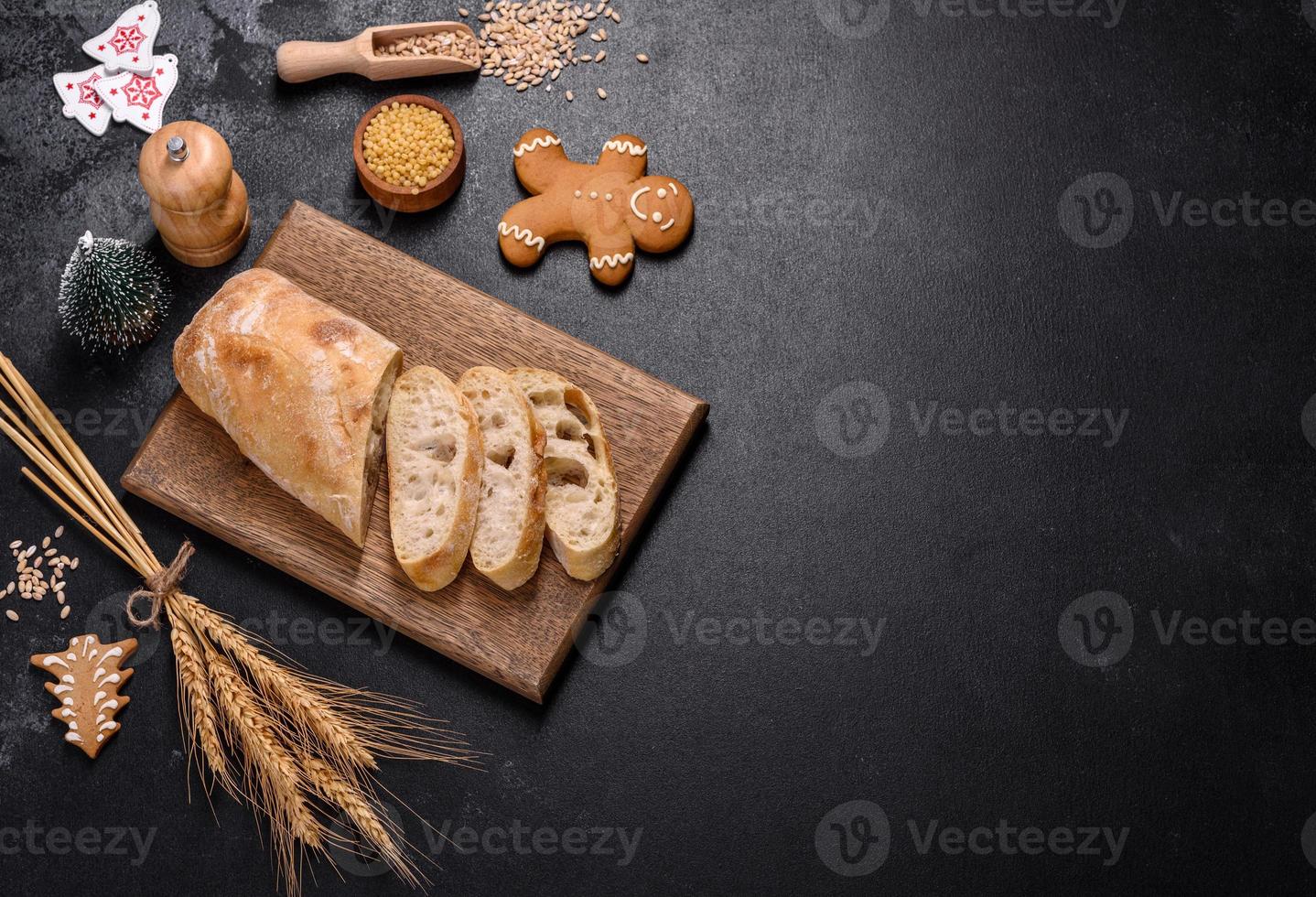 baguette francese tagliata a fette su un tagliere di legno su uno sfondo di cemento scuro foto