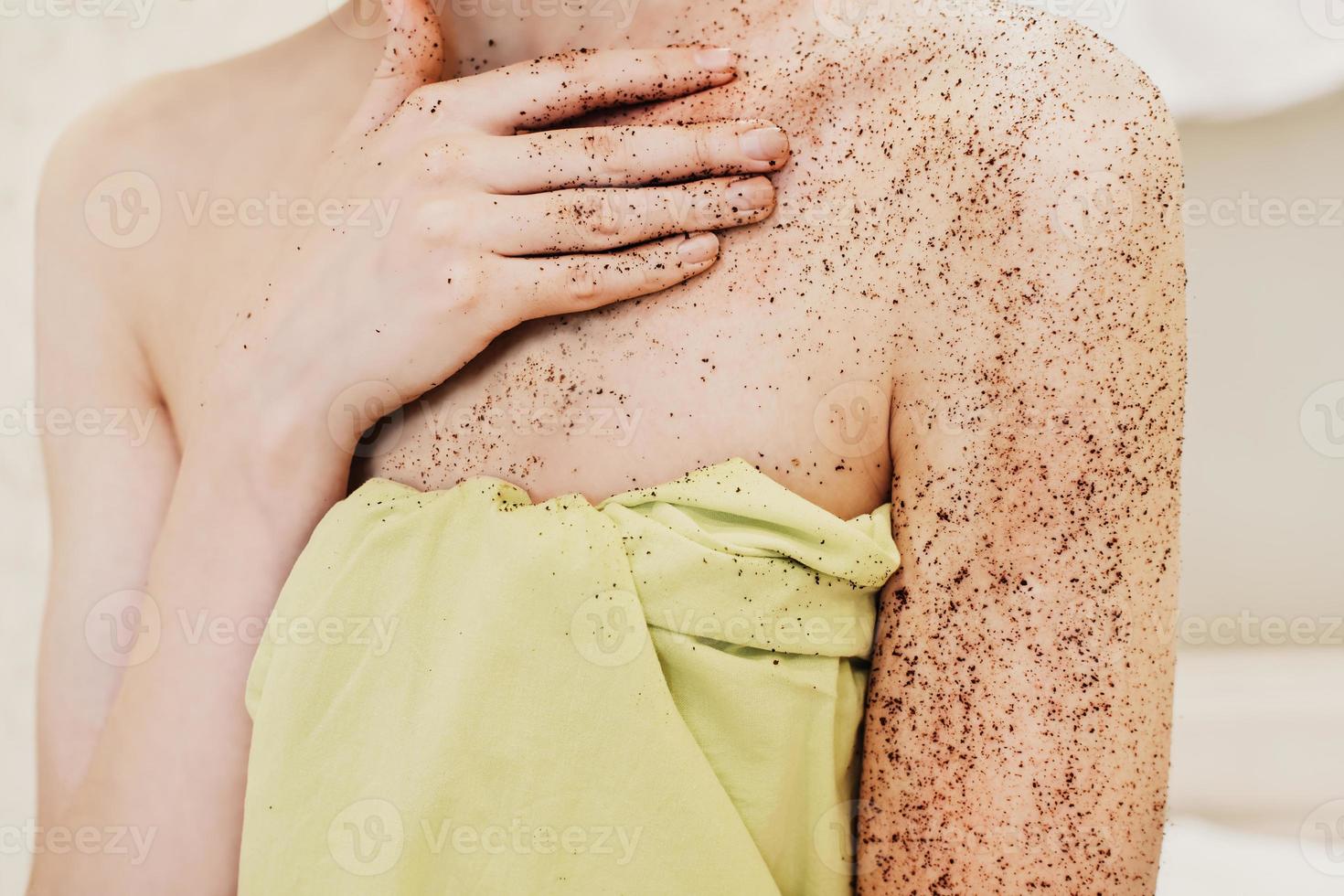 donna che applica uno scrub esfoliante per il corpo. smalto naturale per caffè biologico sulle mani e sul seno di una donna. vista ritagliata. concetto di spa domestica foto