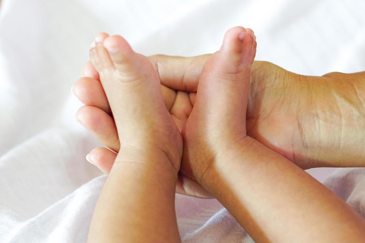 piccoli piedi del bambino o piedi del neonato posti sul palmo della madre e lo sfondo sono pannolini bianchi. foto