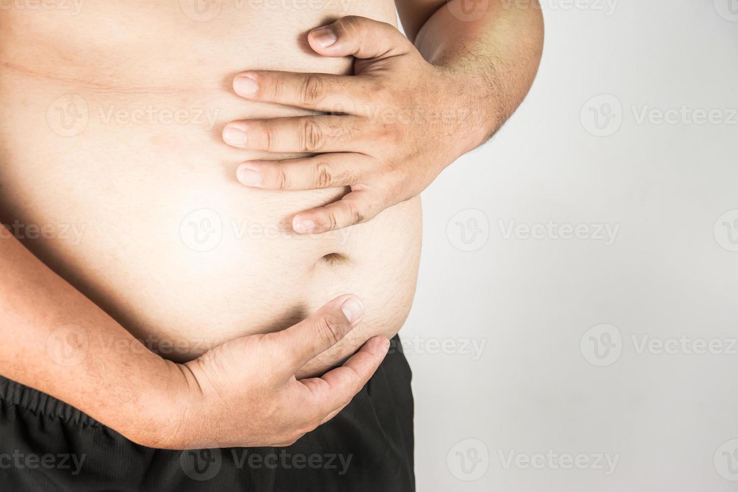 corpo di uomo in sovrappeso con le mani che toccano il grasso della pancia foto