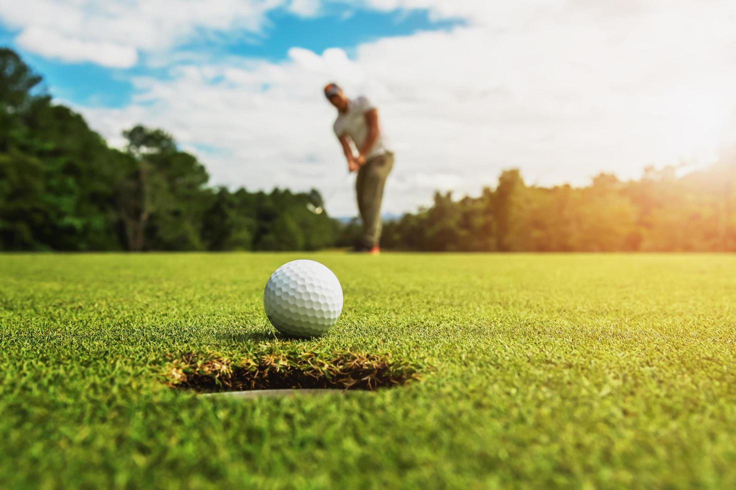 giocatore di golf che mette la pallina da golf nella buca foto