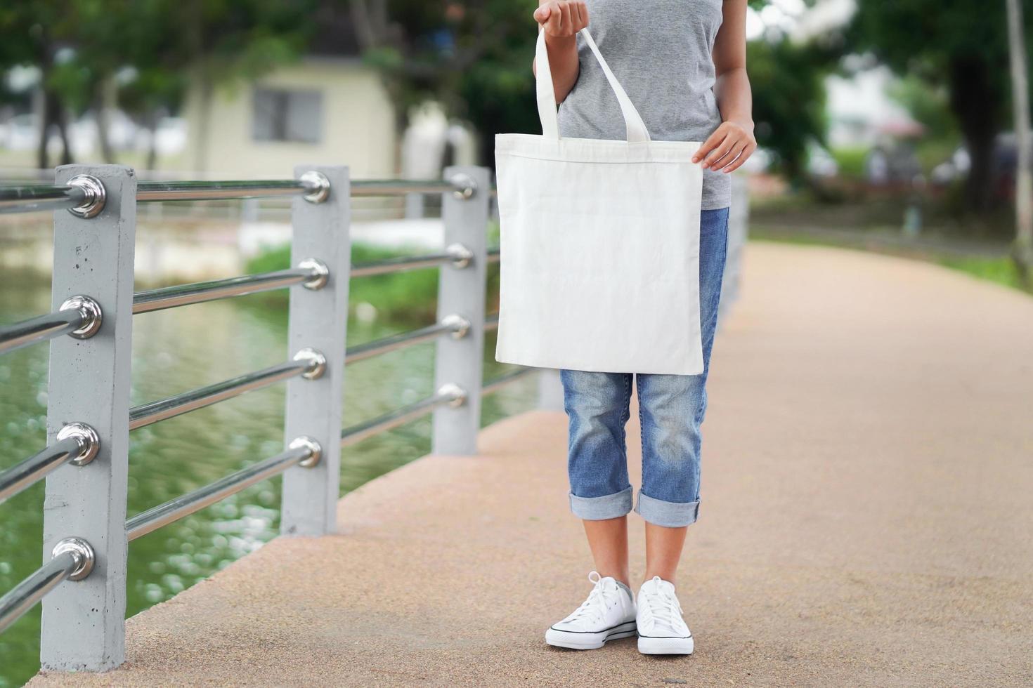 donna hipster che tiene una borsa bianca per mock up modello vuoto foto