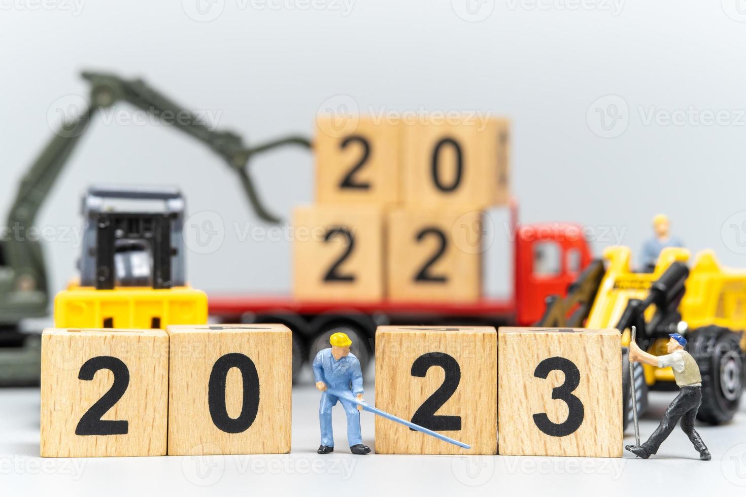 la squadra di lavoratori in miniatura crea il numero 2023 su un blocco di legno foto