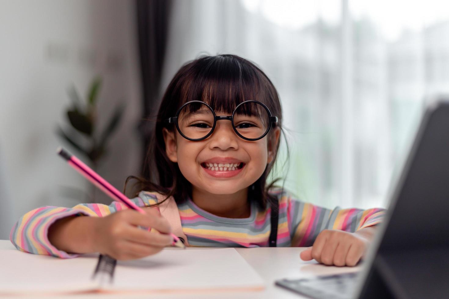 studentessa asiatica in classe di apprendimento online studia online con l'insegnante, ragazza felice impara la lingua inglese online con il tablet a casa. nuova normal.covid-19 coronavirus.distanziamento sociale. stare a casa foto