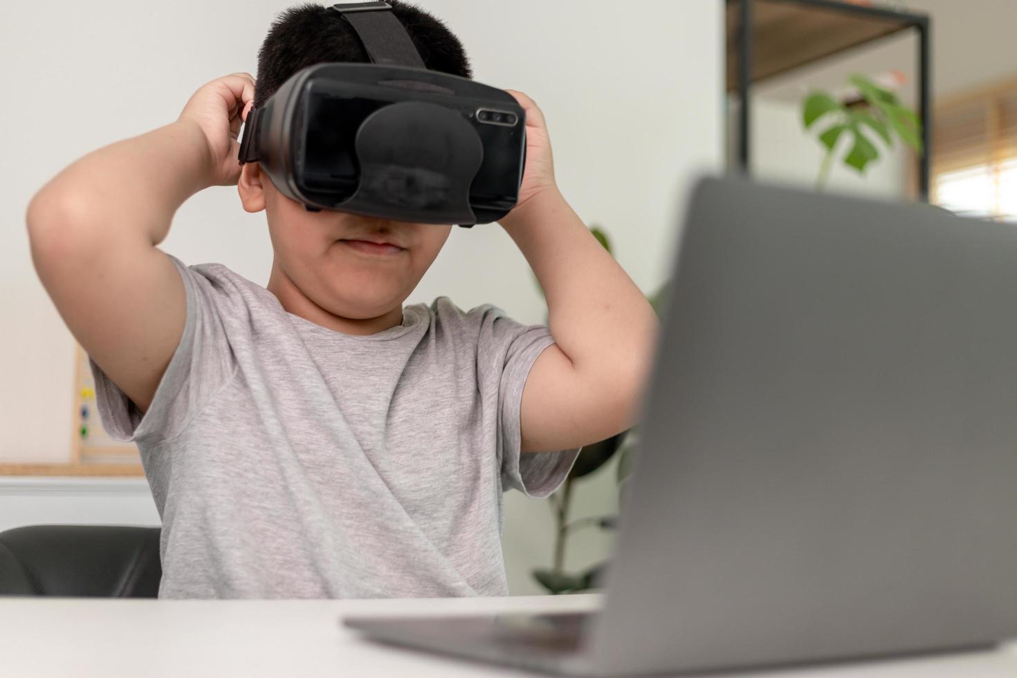 ragazzino asiatico con occhiali vr che studia scienze a casa, uno studente curioso indossa un auricolare per realtà virtuale per studiare scienze a casa studio online stile di vita futuristico apprendimento foto