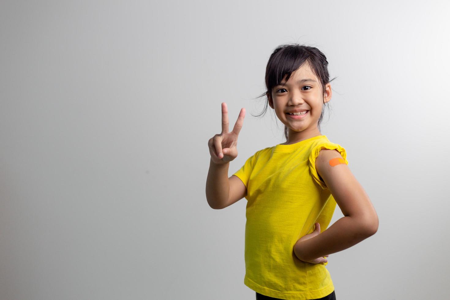 covid 19 vaccini per il concetto di bambini. studio un ritratto di un'adorabile ragazza asiatica dopo aver ricevuto la sua prima dose di vaccino. immuni, sicuri, disponibili, si torna a scuola. foto