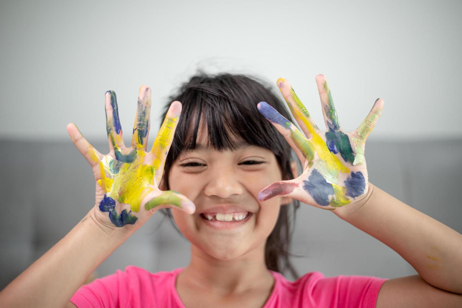 concetto di educazione, scuola, arte e pittura - piccola studentessa che mostra le mani dipinte foto