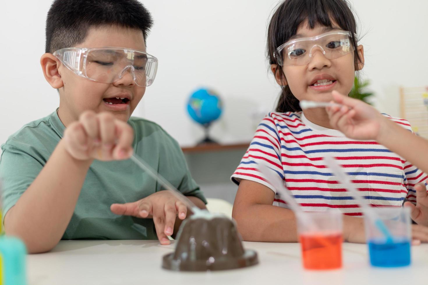 bambini che ripetono e osservano un progetto di laboratorio di scienze a casa: il vulcano di bicarbonato di sodio e aceto foto