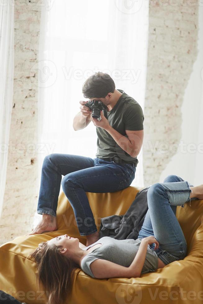 fotografo che scatta una foto della giovane ragazza sdraiata sul divano bianco