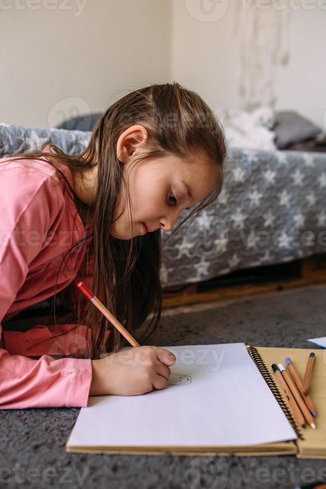 la ragazza dopo la scuola gioca a casa, disegna con matite e pennarelli foto