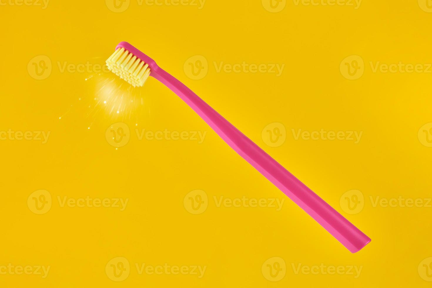 spazzolino rosa su sfondo giallo per l'igiene orale per pulire denti, gengive e lingua foto