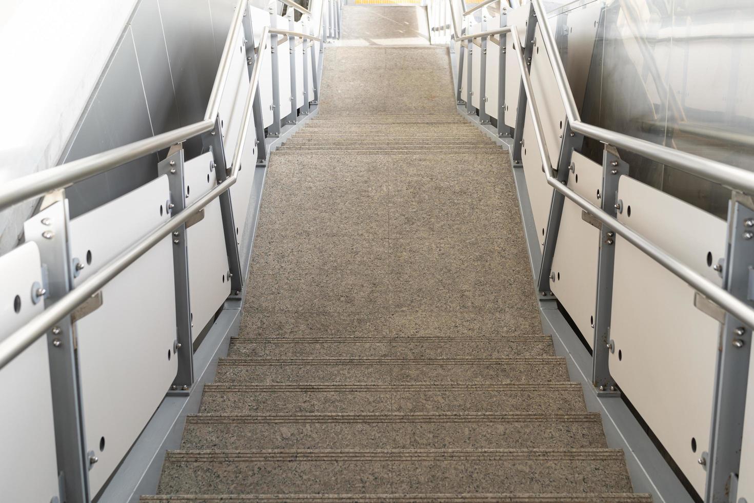 scala pubblica in stazione o centro commerciale per uscita, ingresso. scala all'interno della metropolitana con corrimano in acciaio pulito. una scala vuota in una stazione della metropolitana foto