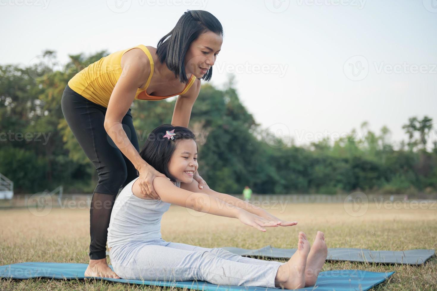 madre e figlia che fanno yoga. donna e bambino che si allenano nel parco. sport all'aperto. stile di vita sportivo sano, seduto in esercizio paschimottanasana, posa seduta piegata in avanti. foto