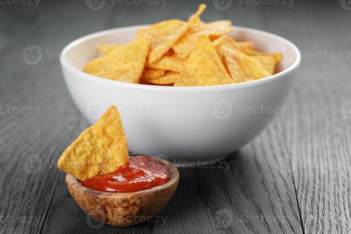 tortilla chips in una ciotola bianca con salsa di pomodoro sul tavolo foto
