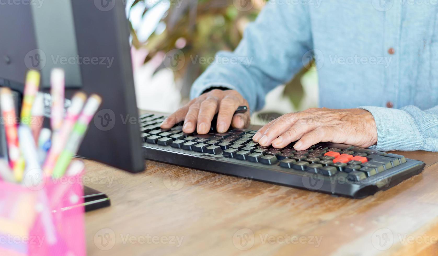 mani di un uomo asiatico che digita su una tastiera bilingue in tailandese e inglese su un computer. foto