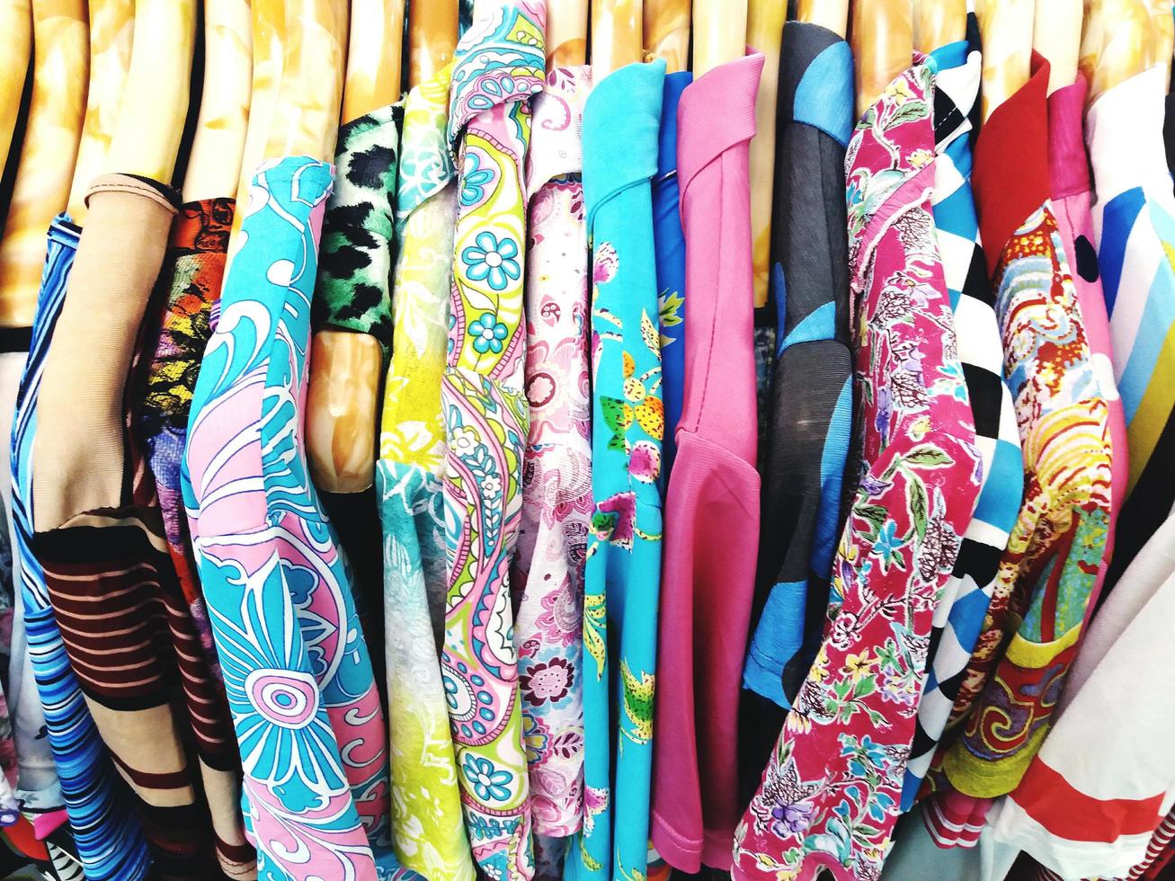 multicolore di abbigliamento. molti colorati di vestiti su appendiabiti di legno. foto