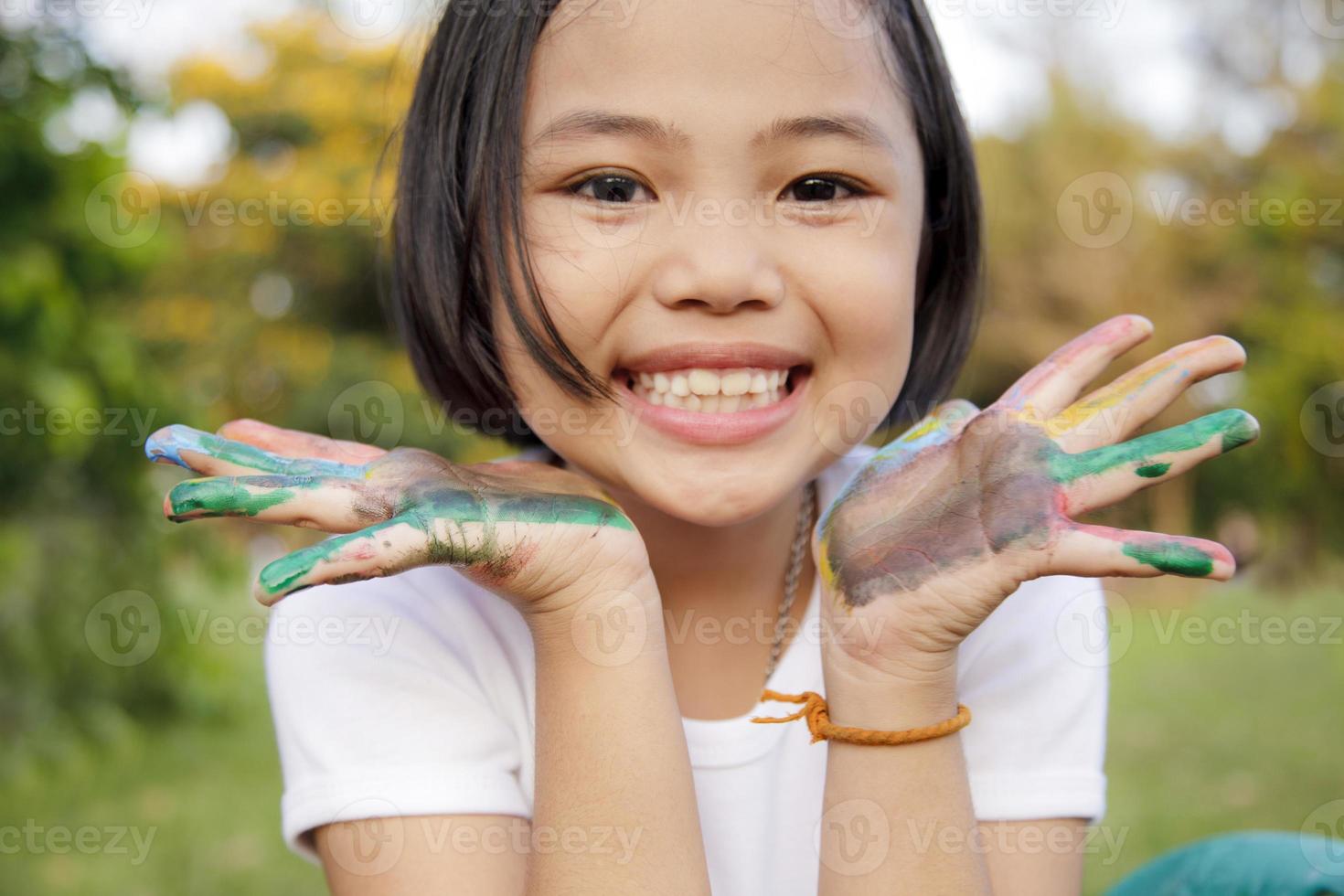 bambina asiatica con le mani dipinte con vernici colorate foto