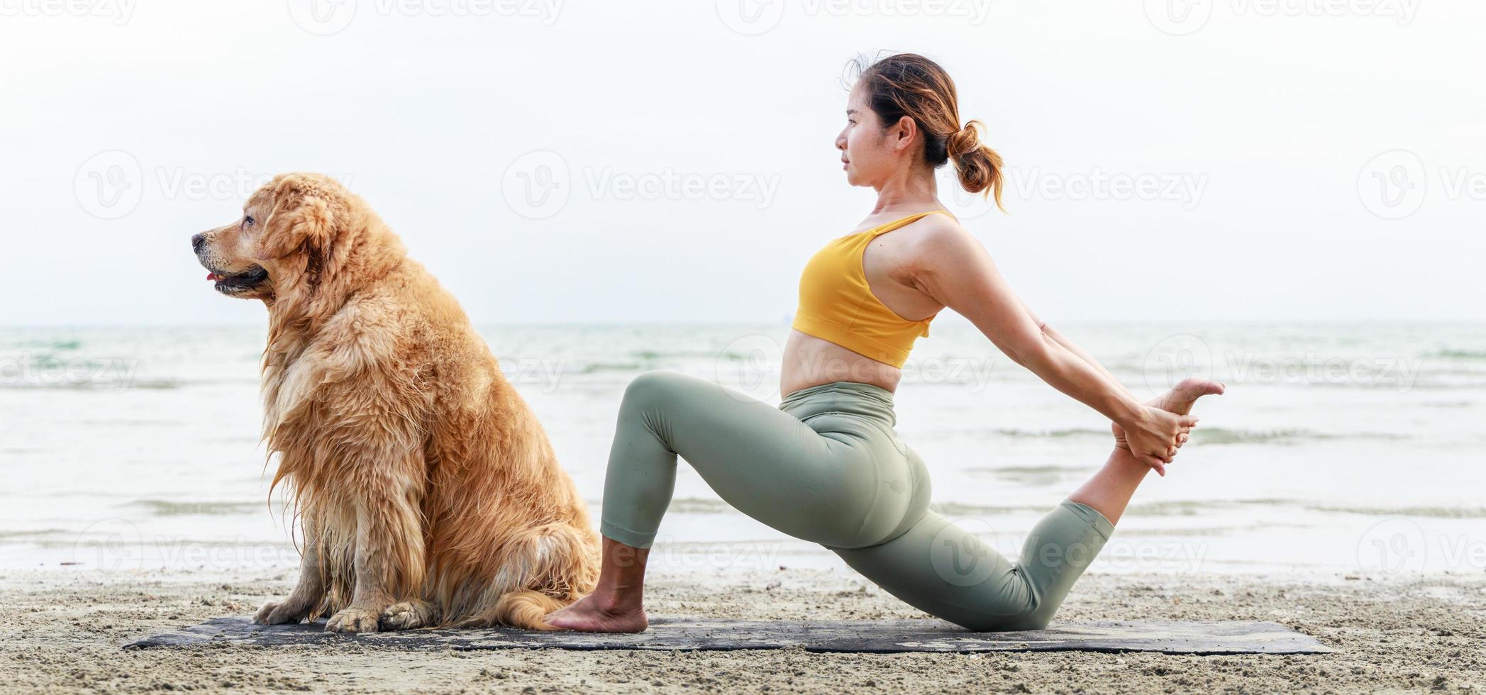 giovane donna asiatica che fa yoga con il suo cane su una stuoia di yoga sulla spiaggia. foto formato banner