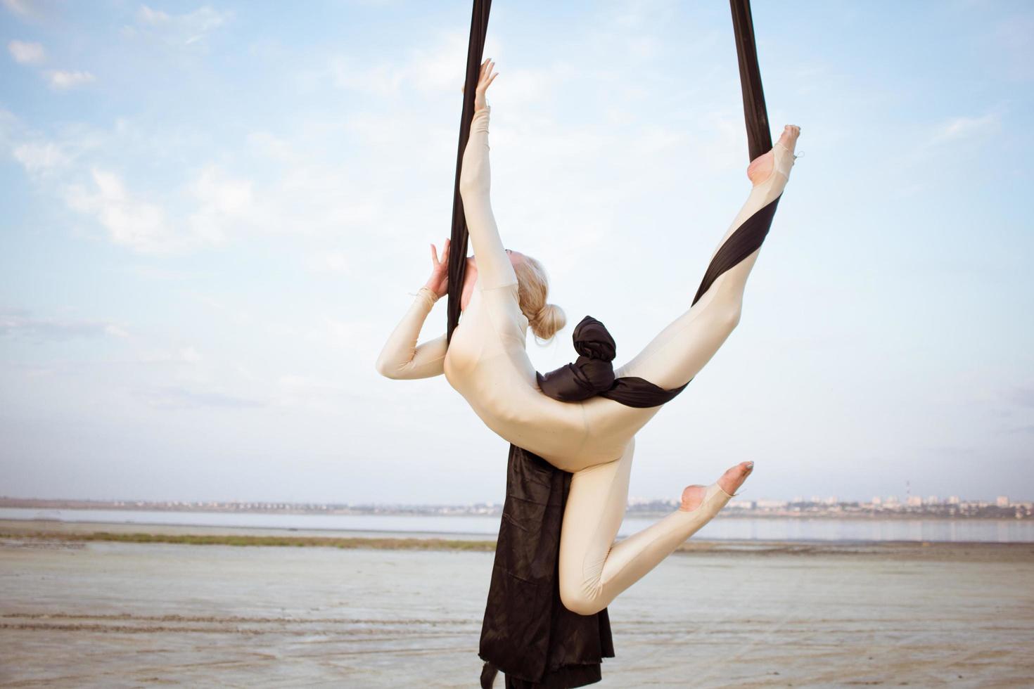 esercizi con seta aerea all'aperto, sfondo cielo. bella donna in forma formazione acrobatica in airt. foto