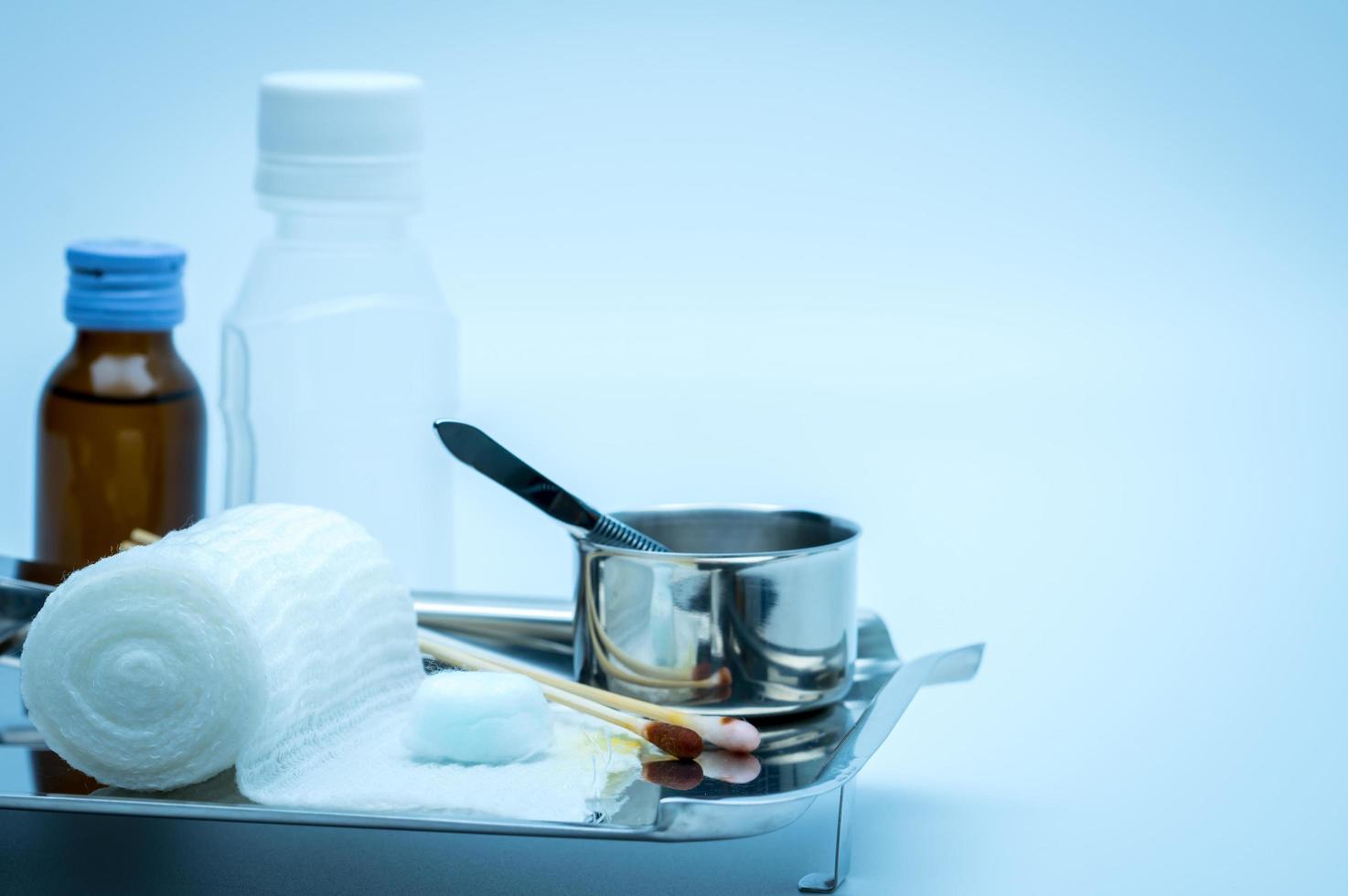 set di medicazioni per la cura delle ferite su piastra in acciaio inossidabile. batuffolo di cotone con alcool, bastoncino di cotone con iodio-povidone, pinza e benda conformata. foto