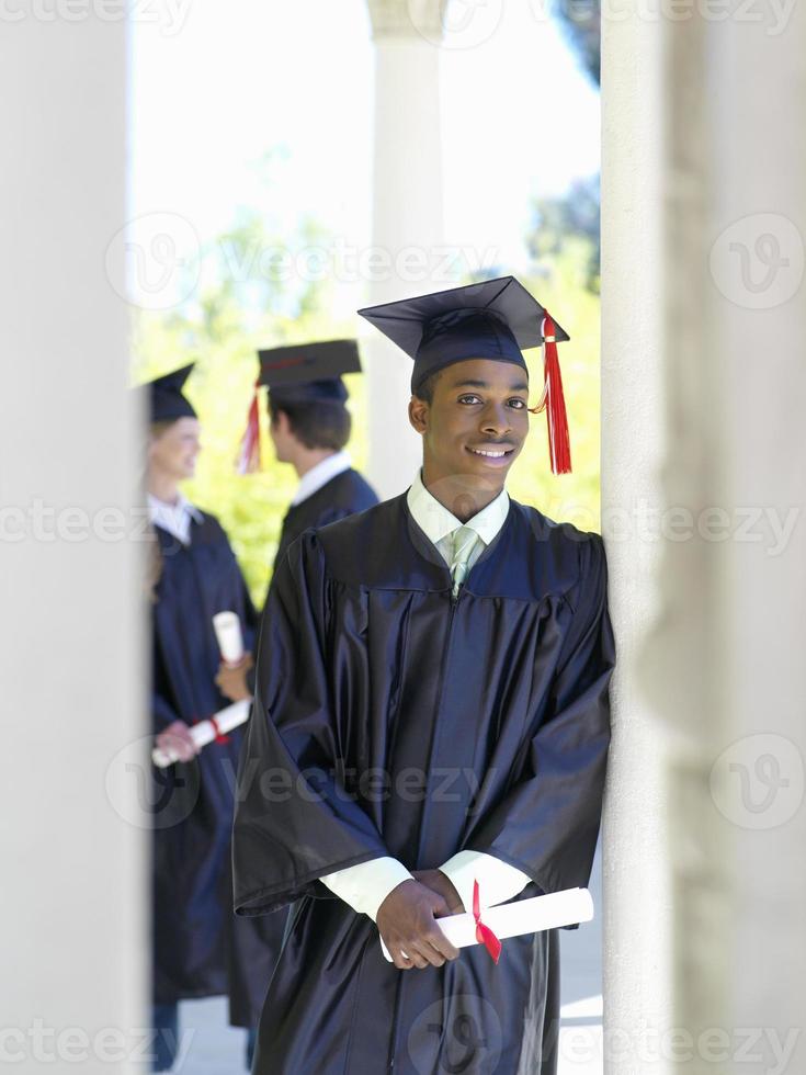 giovane che si diploma in abito accademico in possesso di diploma foto