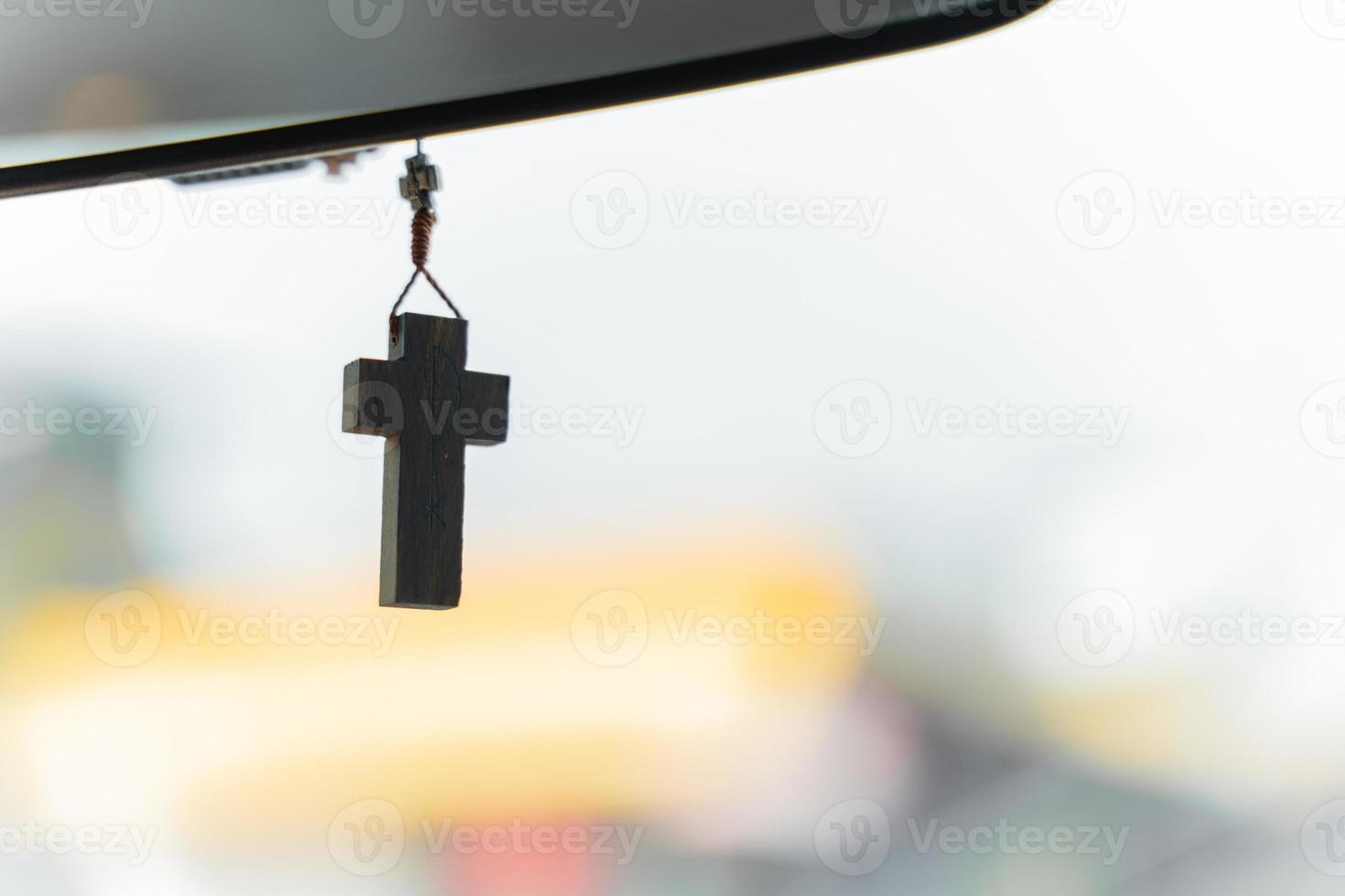 crocifisso cristiano appeso allo specchietto retrovisore dell'auto. concetto di religiosità e fede in dio foto