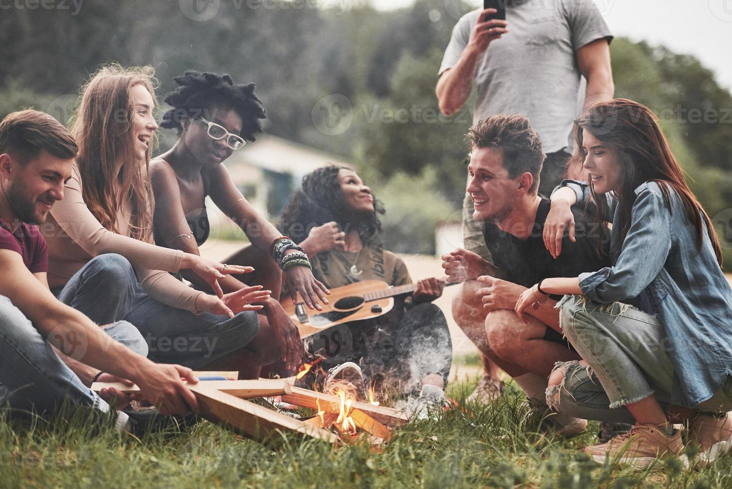 riposa vicino al fuoco. un gruppo di persone fa un picnic sulla spiaggia. gli amici si divertono durante il fine settimana foto
