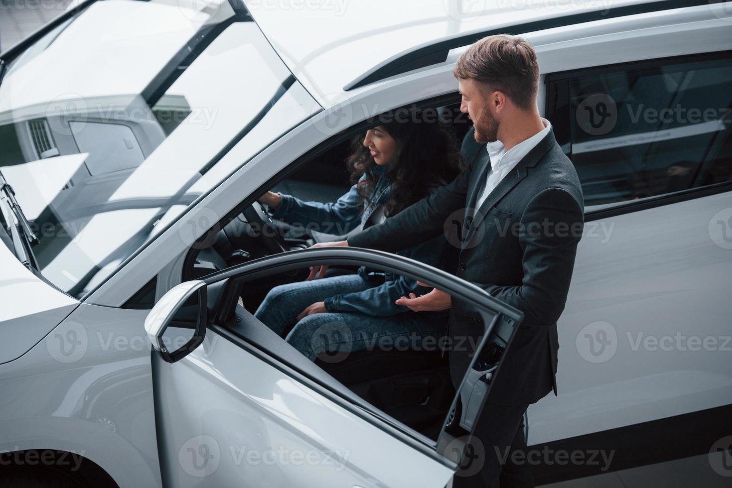 rimarrai colpito. cliente femminile e uomo d'affari barbuto moderno ed elegante nel salone dell'automobile foto