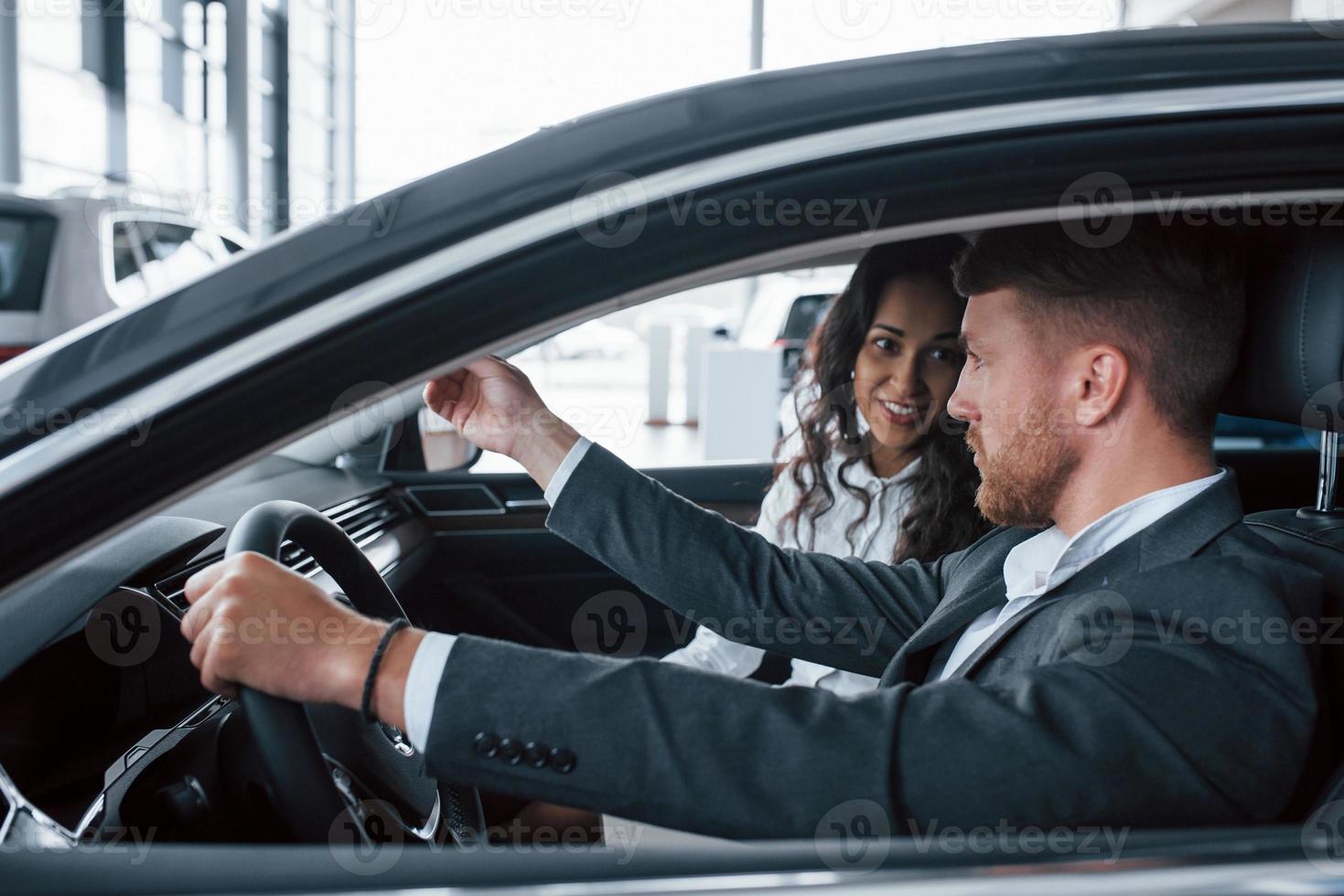 conversazione attiva. bella coppia di successo che prova una nuova auto nel salone dell'automobile foto