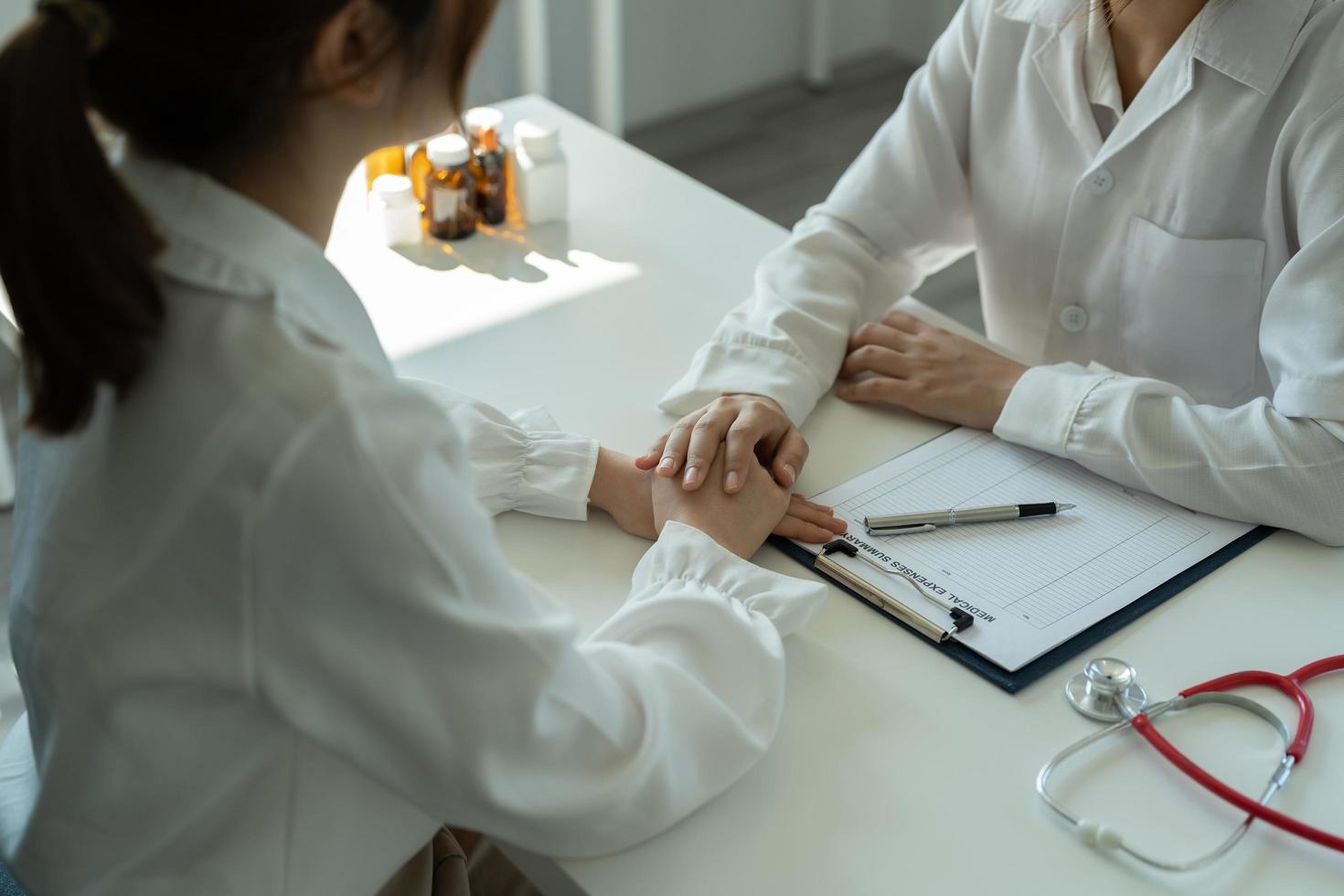 dottoressa asiatica in uniforme medica bianca consultare la paziente in ospedale privato. donna terapeuta parla parlare con la donna cliente durante la consultazione in clinica foto