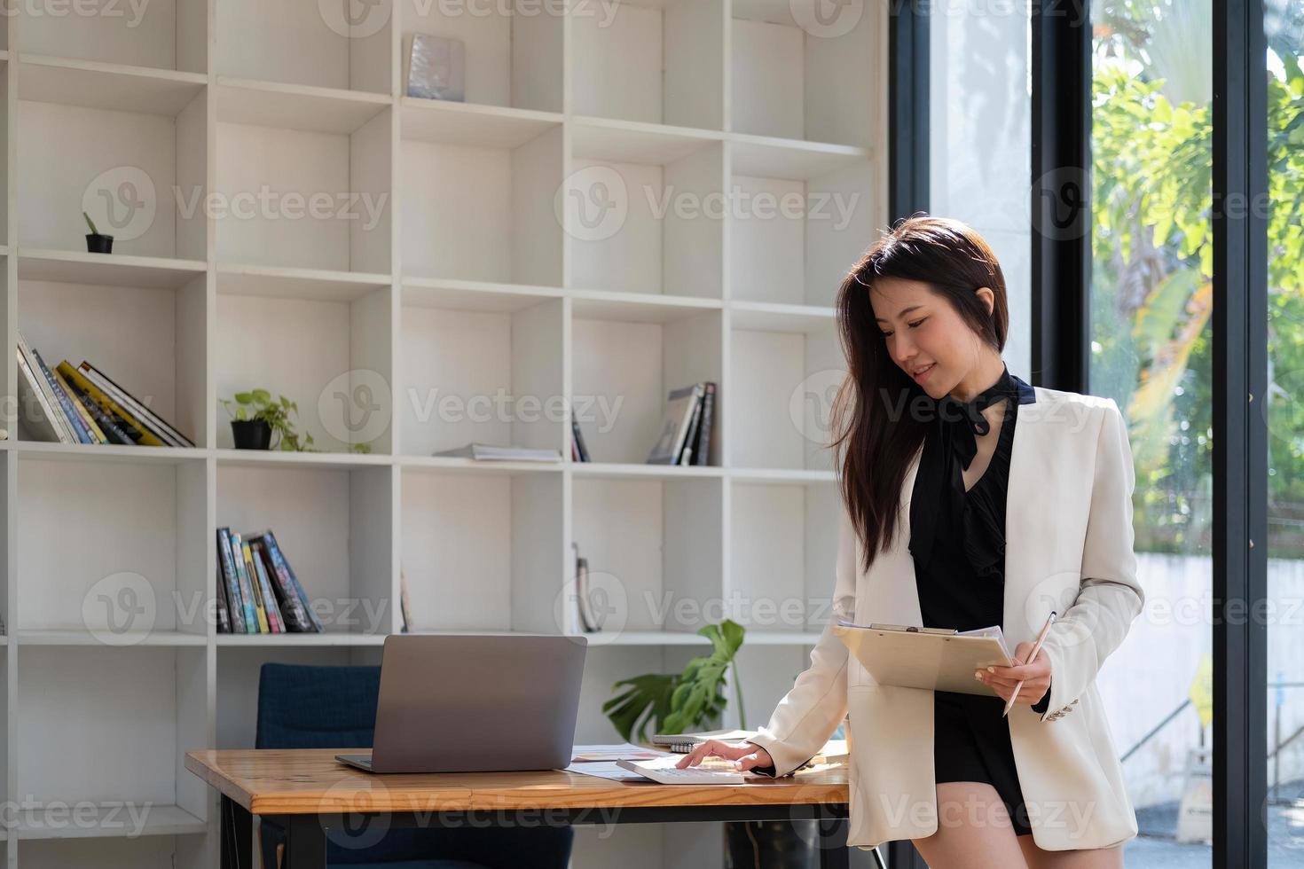 donna asiatica attraente che controlla le tasse, il saldo del conto bancario e calcola le spese nel soggiorno di casa foto