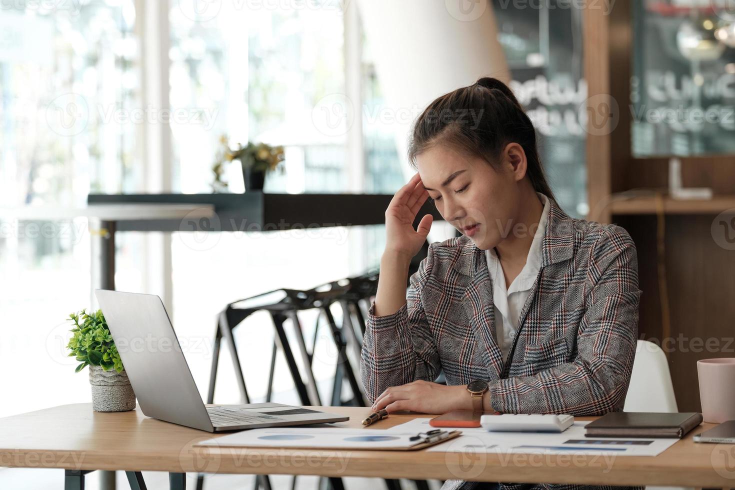 donna d'affari stressata che lavora da casa sul laptop che sembra preoccupata, stanca e sopraffatta. foto