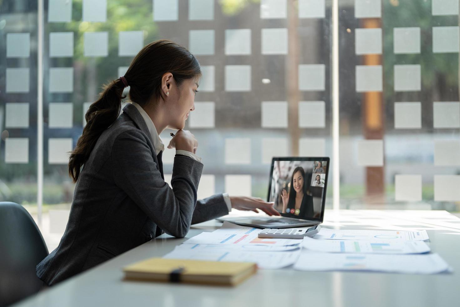 donna d'affari che parla con i suoi colleghi del piano in videoconferenza. team aziendale multietnico che utilizza il laptop per una riunione online in videochiamata. gruppo di persone che lavorano in modo intelligente da casa foto