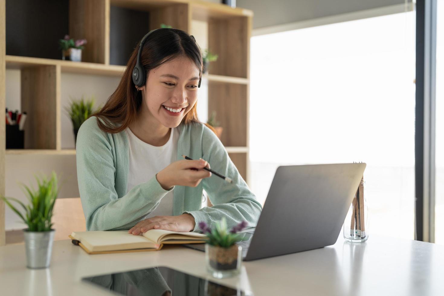 concentrato asiatico gial libero professionista che indossa l'auricolare, comunicando con il cliente tramite videochiamata al computer. insegnante professionista femminile millenaria che tiene lezioni di lingua online. foto