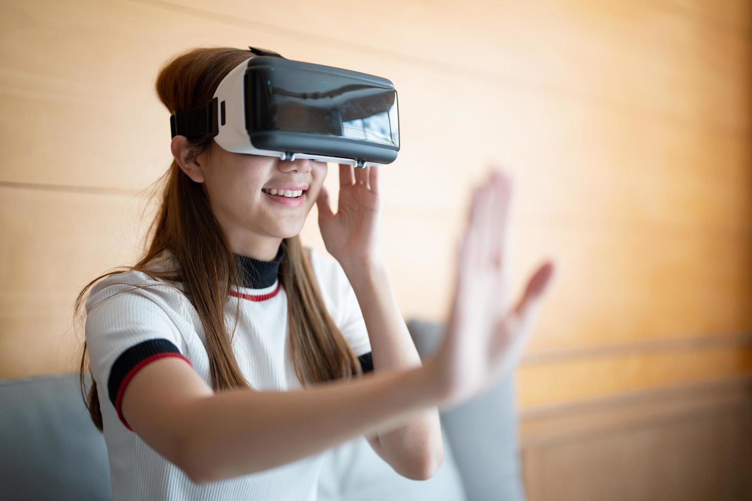 eccitare la donna asiatica che gioca online con occhiali vr e controller a casa sua foto