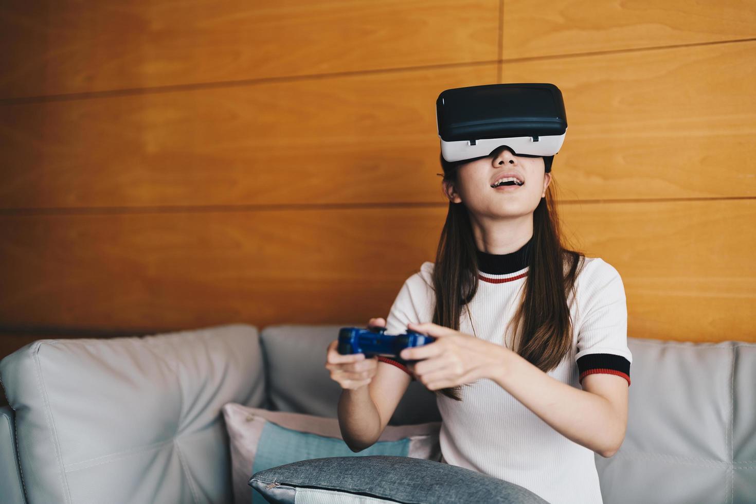 primo piano emozione felice donna asiatica che gioca ai videogiochi con il controller su sfondo astratto tonico con occhiali virtuali foto