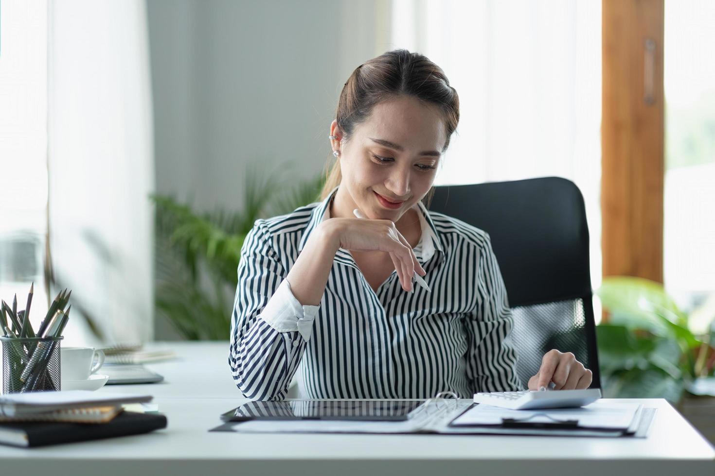 donna d'affari che utilizza la calcolatrice per fare finanza matematica sulla scrivania di legno in ufficio e lavoro aziendale sfondo, tasse, contabilità, statistiche e concetto di ricerca analitica foto