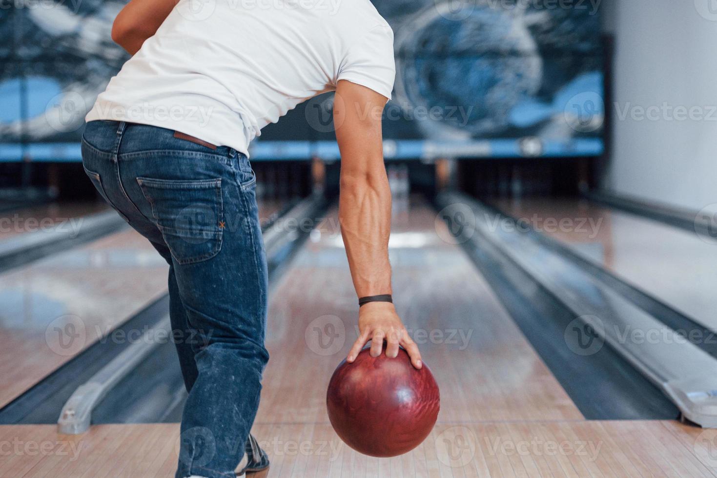 in camicia bianca e jeans. vista posteriore delle particelle di un uomo in abiti casual che gioca a bowling nel club foto