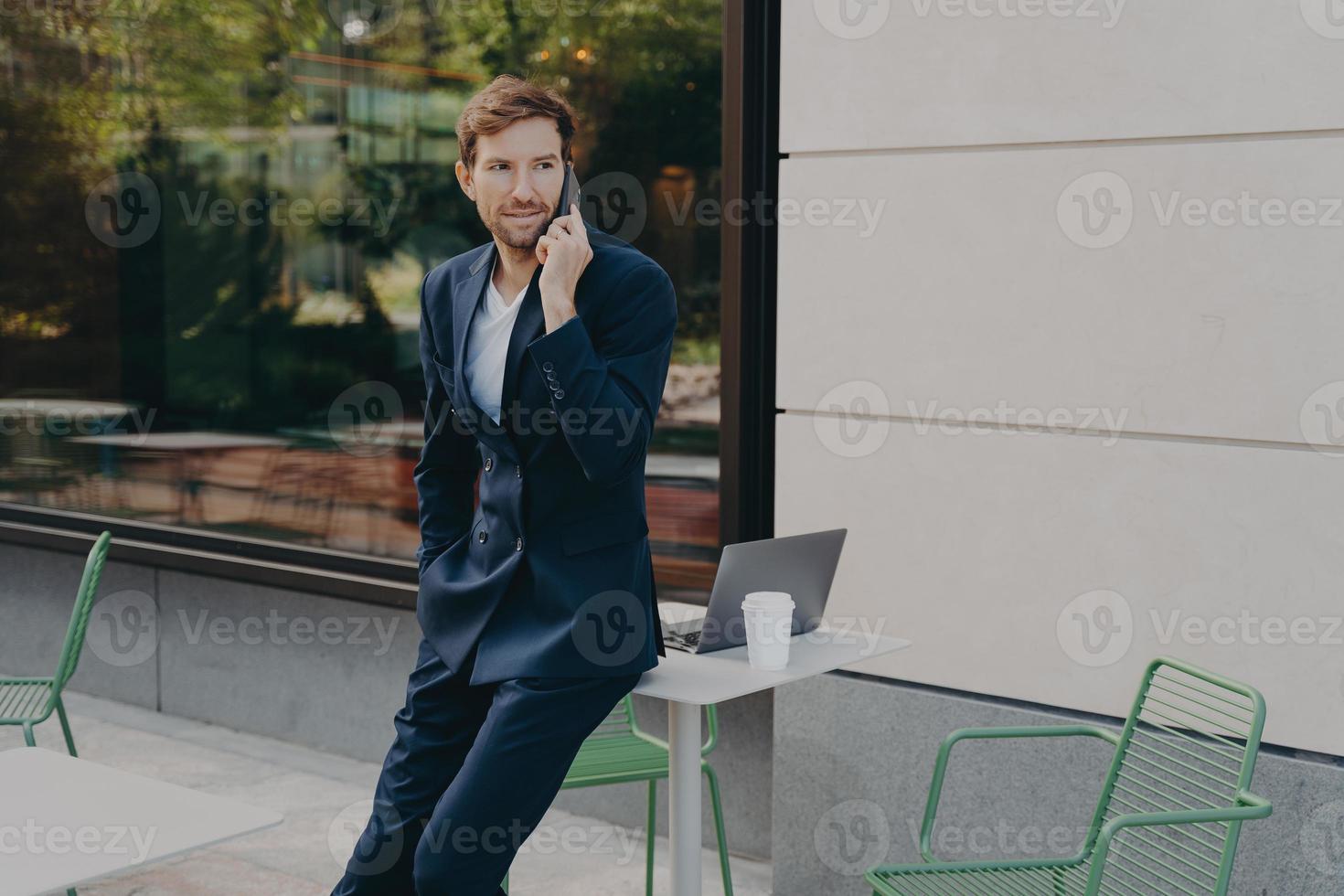 lo scatto all'aperto di un uomo impegnato, l'imprenditore risolve i problemi a distanza ha una conversazione telefonica foto