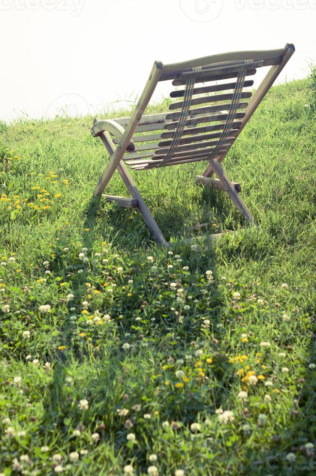 sedia di legno sull'erba sotto la luce solare intensa in estate. foto