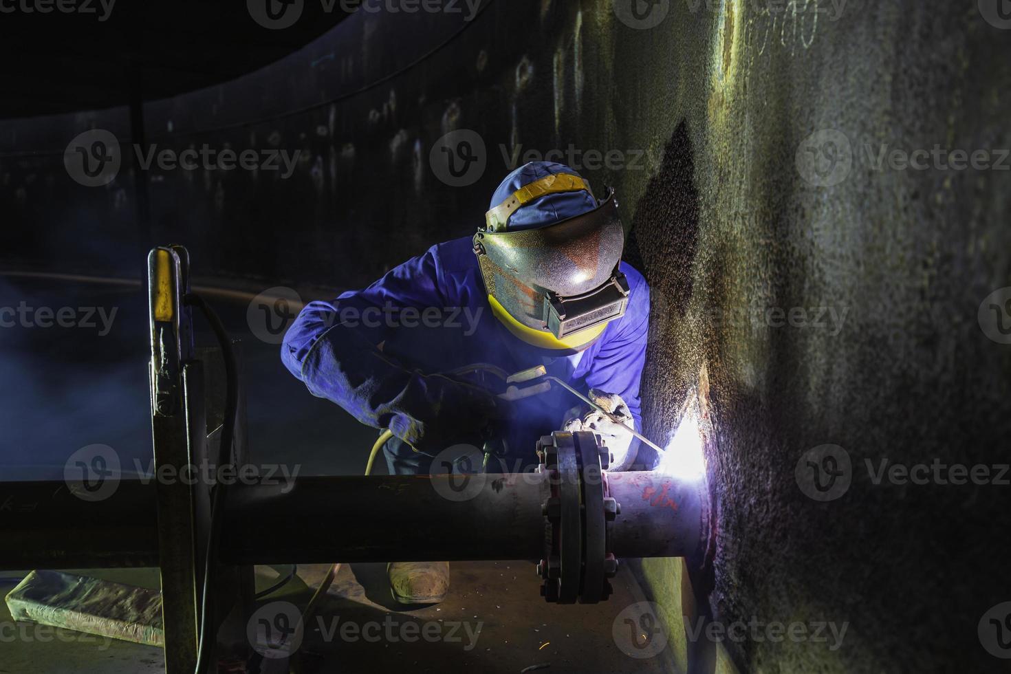 il metallo del lavoratore maschio della saldatura fa parte nella costruzione della conduttura dell'ugello del macchinario foto