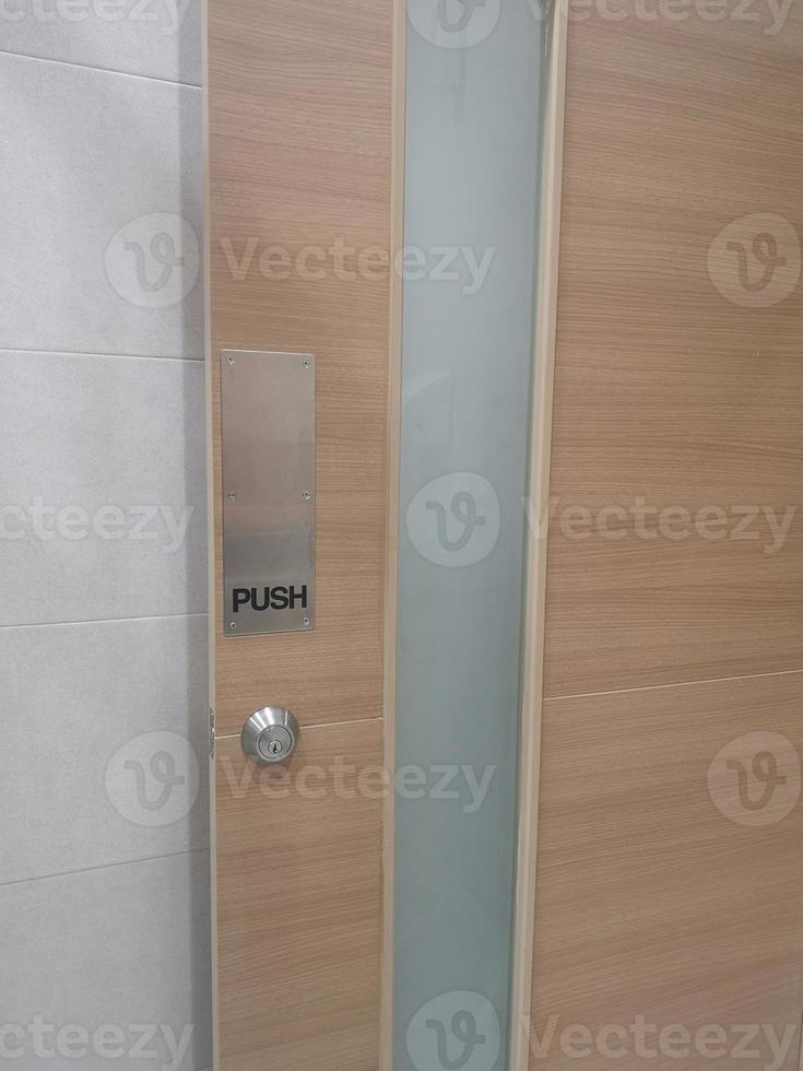 maniglia della porta di tipo push, chiusura con testo nero nella piastra in acciaio inossidabile e foro sulla porta in legno foto